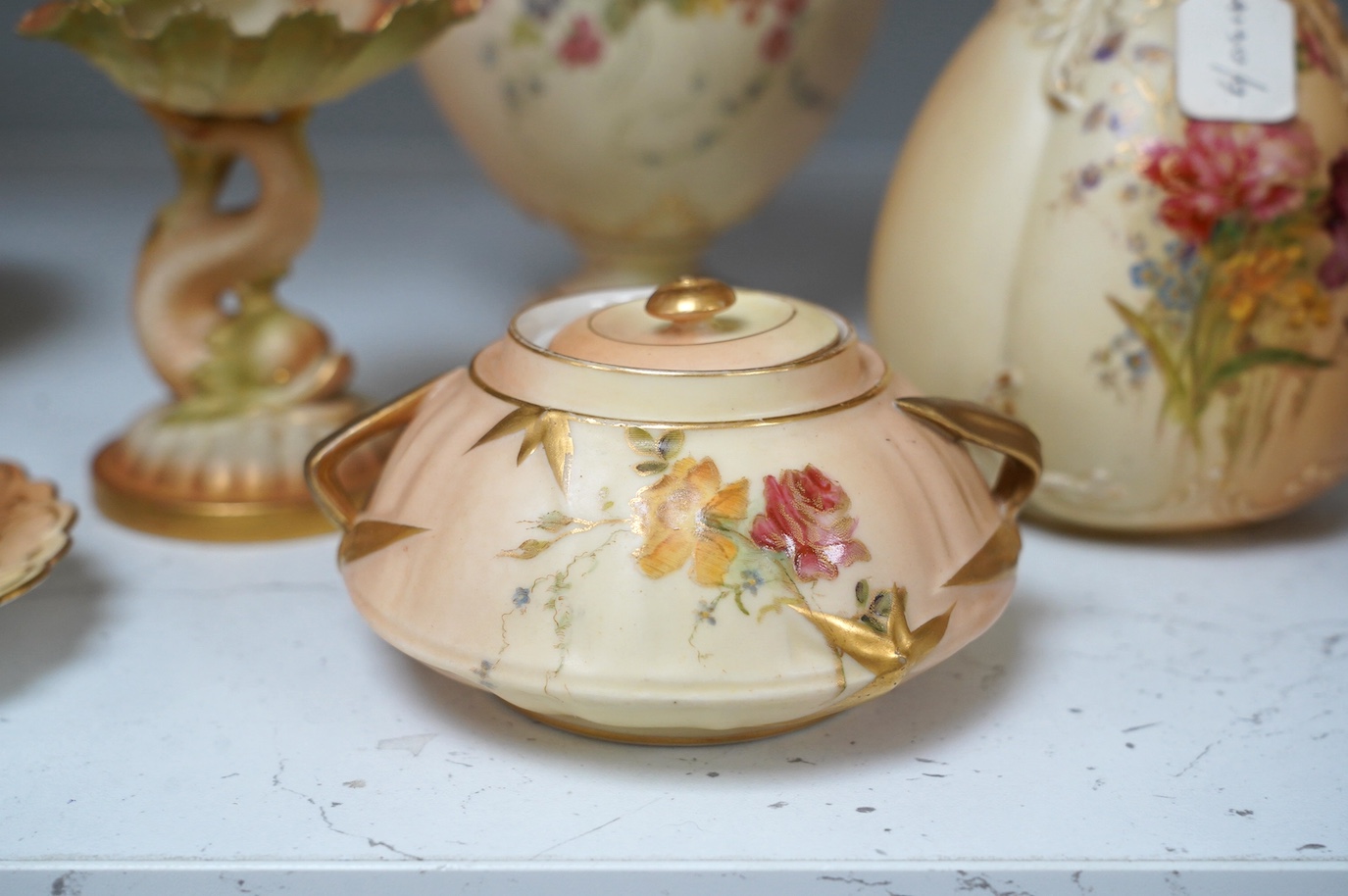 Royal Worcester blush ivory ornamental items: including a vase, two pots and covers, two dolphin stands, a cup and saucer and pierced bowl and cover (8). Condition - fair to good